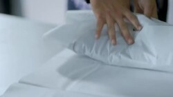 Cashier wraps and bags shirt and shakes customer's hand at checkout counter Stock Footage