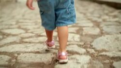 Toddler's feet walk down cobblestone-street in third-world country Stock Footage