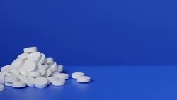 Pile of white pills on blue background Stock Footage