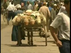 MS Man pulling rickety cart away from camera, down busy street, Egypt Stock Footage