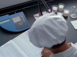 High angle medium shot lab technician recording measurements from digital display of pH meter in log book Stock Footage