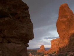 Turret Arch with dramatic morning sunshine and shadows across it's face - pan to dark sandstone cliff Stock Footage