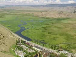 WS AERIAL View of cars running on long highway run besides landscape with mountains / Wyoming, United States Stock Footage
