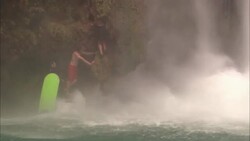 Several teenagers climb a cliff near a cascading waterfall. Stock Footage