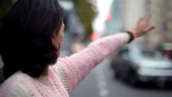Young woman hails a taxi-cab on busy city street-corner Stock Footage