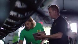 Store manager holds tablet computer and walks employee through bike shop hanging price tags Stock Footage