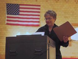 November 2, 2010 MS A voter filing her completed ballot with an American flag on the wall behind her / Dearborn, Michigan, United States Stock Footage