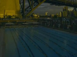 T/L MS ZO Day turns to night and lights come on swimmers doing laps in North Sydney Olympic Pool in shadow of Sydney Harbour Bridge / Sydney, New South Wales, Australia Stock Footage