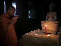 MS, TU A Buddhist monk prays to a Buddha statue lit by candles in an ancient temple in Angkor Wat / Siem Reap, Cambodia Stock Footage