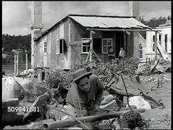 1945: PHILIPPINE POST WWII: WS Ruined, destroyed homes, buildings. MS Philippine man standing over fire, rubble BG. WS Philippine people on line for food ration. MS Men scooping rice into tin cans. CU Man filling tin can w/ rice. CU Women on line. Instructional Video