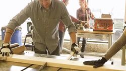 Young trendy man cutting board with table saw in workshop Stock Footage