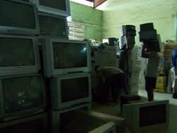 MS PAN interior of warehouse with people stacking old television and computer screens / Lagos, Nigeria Stock Footage
