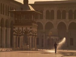 Man using hose in Umayyad mosque courtyard, pigeons fly off from ground, Syria (sound available) Stock Footage