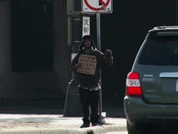 Homeless man with sign on a street corner Stock Footage