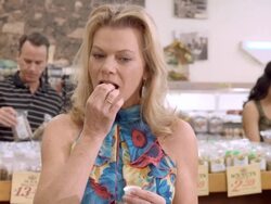 MS middle-aged woman in health food store samples fresh nuts by taking a bite and tasting  / Cabazon, California, USA Stock Footage