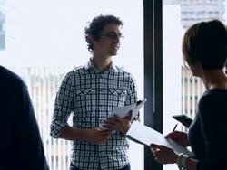 MS DS Businessman standing leading discussion with coworkers at workstation in office/Washington, USA Stock Footage