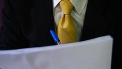 Man signing a document or writing correspondence with a close up view of his hand with the pen and sheet of notepaper on a desk top. Stock Footage