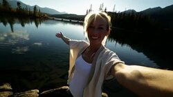 Young woman by the lake taking a selfie portrait at sunset Stock Footage
