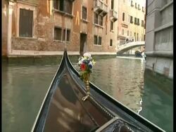 POV from Gondola, Travelling down canal as it turns corner; flowers on bow in foreground, Venice Stock Footage