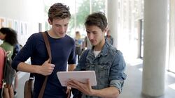 Two male students looking at digital tablet in college corridor Stock Footage