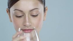 Close-up of young woman with glowing skin drinking a glass of water Stock Footage