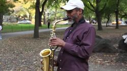 A street musician plays a saxophone in a park. Stock Footage