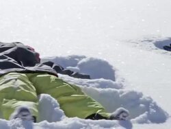 A young boy makes a snow angel on a sunny, winter day Stock Footage