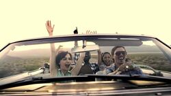 Friends driving through desert in red convertible throw hands in the air Stock Footage