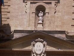 A statue stands in an alcove below a clock tower. Stock Footage