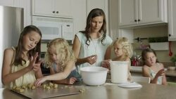 Medium panning shot of mother and daughters rolling cookie dough / Orem, Utah, United States Stock Footage