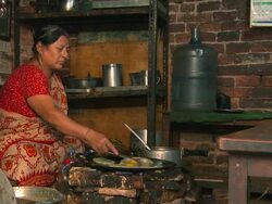 Nepali woman cooking food over a fire. Stock Footage