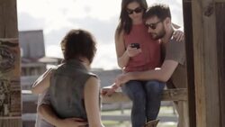 Young couple laugh with friends and kiss on wooden fence in Texas ghost town Stock Footage