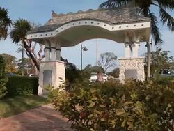Blond girl entering the park, passing under a nice archway Stock Footage