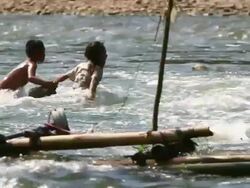 MS TS SLO MO Shot of Two children holding each other trying to cross river and fighting against current water/ Muang Ngoi, Luang Prabang, Laos Stock Footage