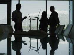 Panning silhouette of business people looking at model wind turbines in conference room then shaking hands / Provo, Utah, United States,  Stock Footage