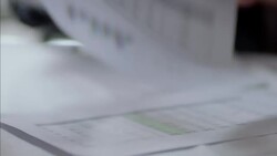 Financial advisor digs through paperwork in business meeting Stock Footage