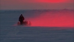 Dogs pull a man on a sled over the Alaskan tundra at sunset. Stock Footage