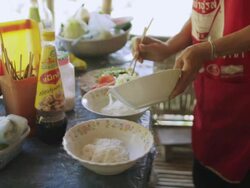  MS TU SLO MO  Woman in red apron putting vegetables on top of noodles in bowls / Vang Vieng, Vientiane, Laos Stock Footage