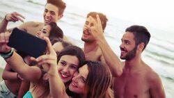 Group of friends taking selfies on the beach Stock Footage