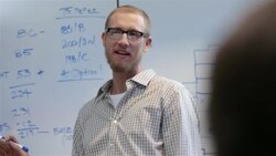 Young businessman instructs team from conference-room white-board Stock Footage