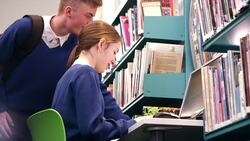 Boy and girl studying at computer in school library Stock Footage