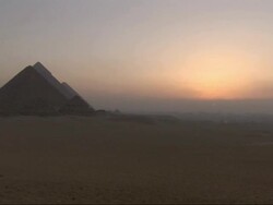 Wide Shot, static - A golden-hour sky silhouettes the Pyramids of Giza in Egypt Stock Footage
