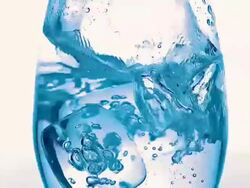 CU SLO MO Ice cubes falling into glass of water against Blank Backdrop / Vieux Pont en Auge, Normandy, France Stock Footage