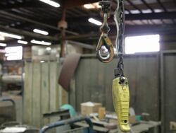 Caucasian factory worker hooking strap on crane hook and picking up controls Stock Footage