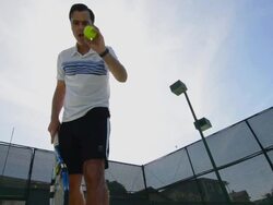LA WS of a man bouncing and serving a tennis ball with the sun behind him. Stock Footage
