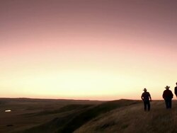 Three cowboys walk in the prairies with a pinky sunset Stock Footage