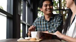 Asian man and woman talk together in coffee cafe Stock Footage