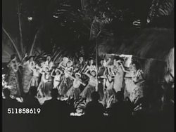 1950: HAWAII: TOURISM: NIGHT: HA WS Indigenous native people, Hawaiian dancers, women, young girls dancing hula in flower leis & grass skirts for tourists sitting FG.  Polynesian, culture, cultural, Iconic. Instructional Video