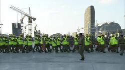 A group of soldiers wearing reflective vests marches, then stands at attention. Stock Footage