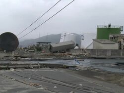 Destruction caused by tsunami after magnitude 9 Tohoku earthquake, north east Japan, March 2011. Wide shot of damaged oil storage tanks and truck lying on wall in Ishinomaki City port, Miyagi Prefecture Stock Footage